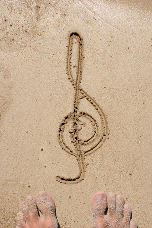 Concept, conceptual music symbol handwritten in sand on a beach backgroundの写真素材