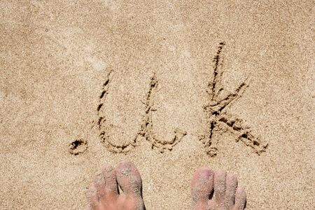 The word .uk handwritten in sand on a beach, ideal for internet or conceptual designs backgroundの写真素材