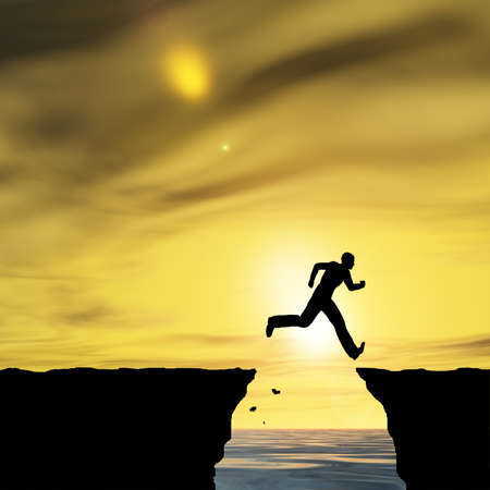 Conceptual business man silhouette jumping at sunset sky backgroundの写真素材