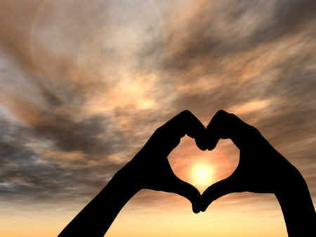 Concept or conceptual heart shape or symbol made of human or woman and man hand silhouette over a sky at sunset backgroundの写真素材