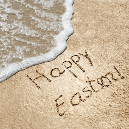Concept or conceptual hand made or handwritten Happy Easter text in sand on a beach in an exotic islandの写真素材