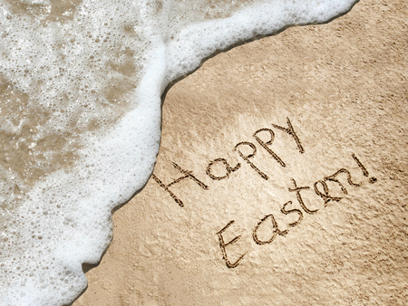 Concept or conceptual hand made or handwritten Happy Easter text in sand on a beach in an exotic islandの写真素材