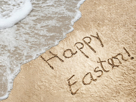 Concept or conceptual hand made or handwritten Happy Easter text in sand on a beach in an exotic islandの写真素材