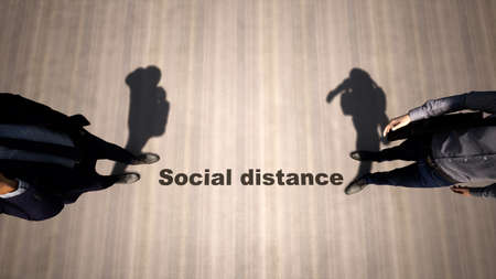 Concept or conceptual 3d illustration of two men meeting following social distance guidelines on a wooden floor background. A metaphor for the change in company relations during the lockdown.の写真素材