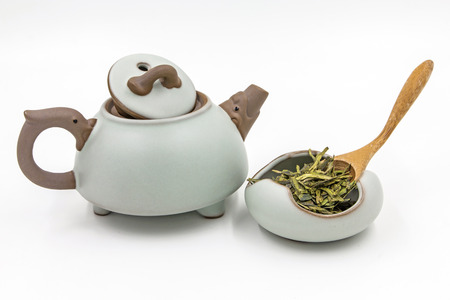 Longjing (Dragon Well) - Chinese green tea with small clay pot and wood spoon isolated on white.の写真素材