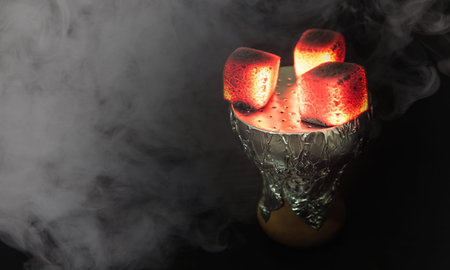 Shisha bowl with craft tobacco and coil in the hookah smoke.