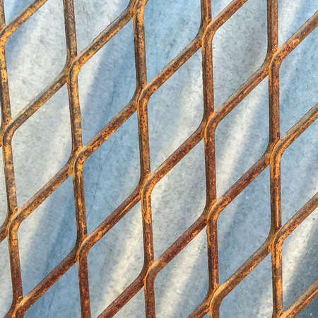 Old Metal mesh fence against zinc backgroundの写真素材