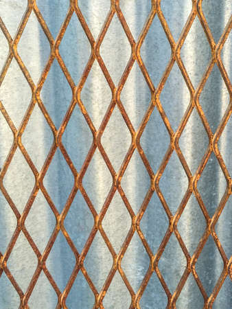Old Metal mesh fence against zinc backgroundの写真素材