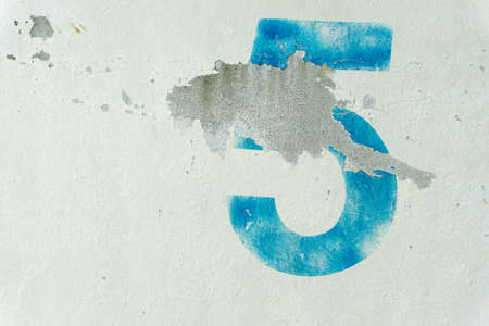 the number 5 on the dirty white wallの写真素材