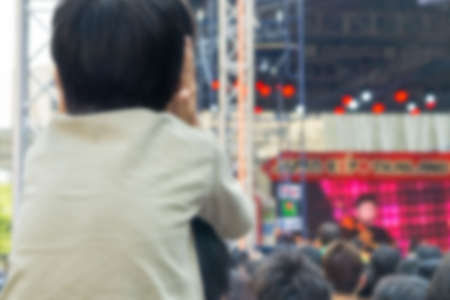 Abstract blurred . A kid cover ear and sitting on the shoulders of his father at outdoor concertの写真素材