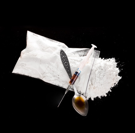 Drug powder, drug syringe and cooked drug on spoon close-up on a black background.の写真素材