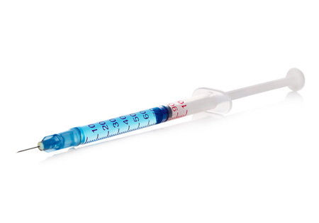 Medical syringe with blue solution close-up isolated on a white background.