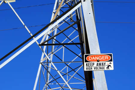 Side of a power pylon with Danger-sign against a clear blue skyの写真素材