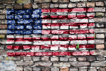 Flag of USA painted on an old brick wall with small ivy plant growing out of a crack.の写真素材