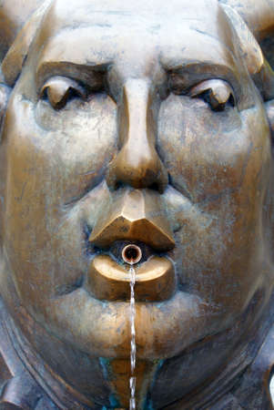Brass face on a fountain with water coming out of a tube from the mouth. Picture taken in South Germany.の写真素材