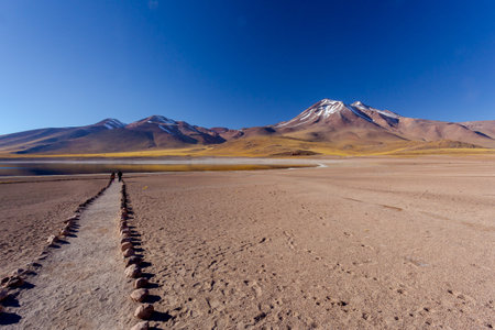 Beautiful Lanscape of Two people walking towars the lagoon. Following a path made by rounded rock.