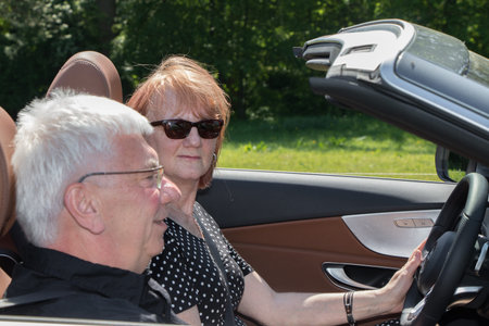 Smiling happy senior couple in sports car on a sunny day