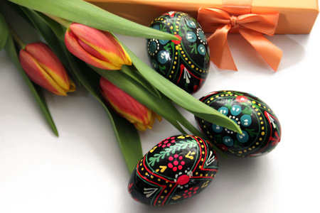 Composition of orange yellow tulips, painted Easter eggs and gift box
