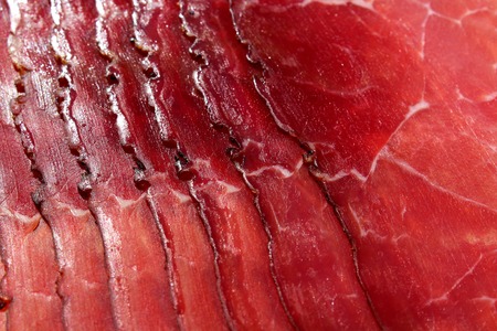 Smoked ham. Italian speck red meat slices isolated on white background. Prosciutto beaf meat slices as texture .の写真素材