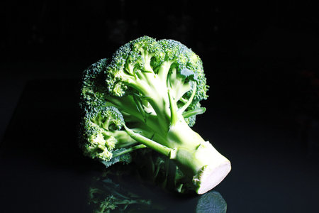 Broccoli. Green whole brokkoli on black reflective studio background. Isolated black shiny mirror...