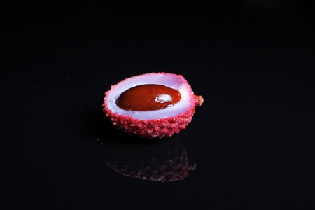 Litchi chinensis. Exotix litchi fruit fruits on black reflective studio background. Isolated black shiny mirror mirrored background for every concept. Litchi.の写真素材
