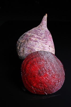 Beet beetroot. Whole and half cutted beet beetroot on black reflective studio background. Isolated black shiny mirror mirrored background for every concept. Beetroot.の写真素材
