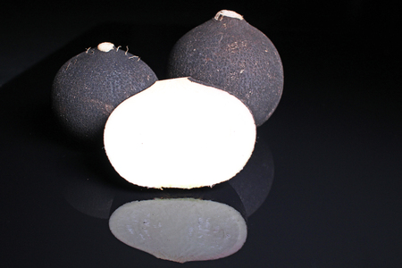 Black raddish. Whole black raddishes on black reflective studio background. Isolated black shiny mirror mirrored background for every concept. Radidsh.の写真素材