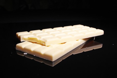 White chocolate bar on black reflective studio background. Isolated black shiny mirror mirrored background for every concept..の写真素材