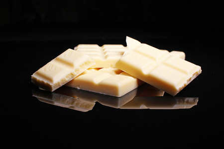 White chocolate bar on black reflective studio background. Isolated black shiny mirror mirrored background for every concept..の写真素材