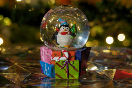 Christmas snow globe ball. Decorating Christmas dome ball before a lit Christmas tree.