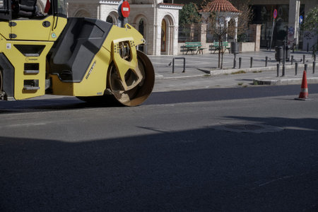 Steamroller presses asphalt at road. Yellow Road roller flattens asphalt at a road reconstruction...