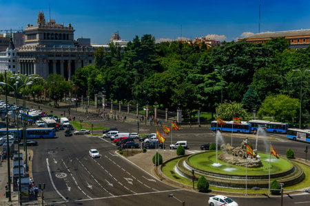 Madrid, Spain Ciberles Fountain with Spanish flags. Public buses and cars traffic around Plaza de Cibeles viewed from Cybele Palace at the Spanish capital.のeditorial素材