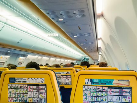 Ryanair aircraft seats view with passengers. Rear view of new seats thinner layout inside a Ryanair Boeing 737 800 aircraft with safety info cards displayed.のeditorial素材