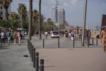 Barcelona, Spain Police patrol at Barceloneta beach area. Police car by the sandy crowded beach, securing beach safety.のeditorial素材