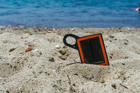 Portable solar charger power bank on the beach. Day view of small orange and black frame sun charger...