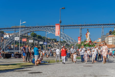 Porto, Portugal Catholic Christian religious holiday procession. Flower decorated statues carried by people on the bank of Douro river at Vila Nova de Gaia, with Luis I Bridge visible.のeditorial素材