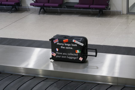 Manchester, UK airport baggage reclaim area security reminder. Manchester airport terminal arrivals empty luggage carousel with message for collecting your personal bag.のeditorial素材