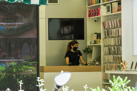 Thessaloniki, Greece Coronavirus measures affect business & daily life. Shop entrance with clerk...
