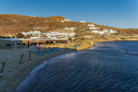 Mykonos, Greece Paradise Beach bar elevated landscape. Evening view of Tropicana seafront complex at Cycladic islands not crowded with empty deckchairs & umbrellas by the sand.のeditorial素材