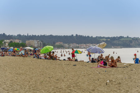 Neoi Epivates, Greece Public beaches open for the summer season. Bathers with sun umbrellas on sand by the sea at Thessaloniki suburbs, after government suggests people keep a distance.のeditorial素材