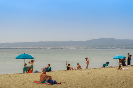 Neoi Epivates, Greece Public beaches open for the summer season. Bathers with sun umbrellas on sand by the sea at Thessaloniki suburbs, after government suggests people keep a distance.のeditorial素材