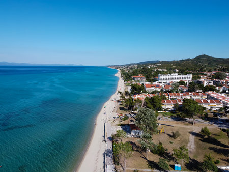 Chalkidiki, Greece coastal village landscape drone shot. Aerial day view of Hanioti or Chaniotis seafront at Kassandra peninsula with low rise buildings by a clean tranquil blue sea.のeditorial素材