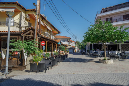 Chalkidiki, Greece - June 18 2020: Almost empty cafe chairs & tables after new covid-19 measures. Day outdoor seating area with a few customers at Hanioti village square, Kassandra peninsula.のeditorial素材