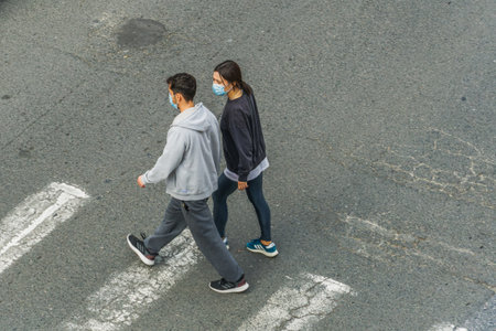 Thessaloniki, Greece - October 24 2010: People with covid-19 masks outdoors. An unidentified couple with face protection walks on a zebra crossing.のeditorial素材