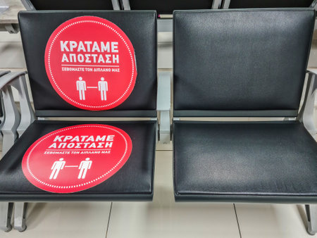 Thessaloniki, Greece - November 10 2020: Keep your distance interior sign in Greek. Chairs sticker suggesting customers keep 1.5 meters away as Coronavirus measures affect business & daily life.のeditorial素材