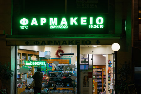 Thessaloniki, Greece November 26 - 2020: Greek open pharmacy store entrance. External night view of...