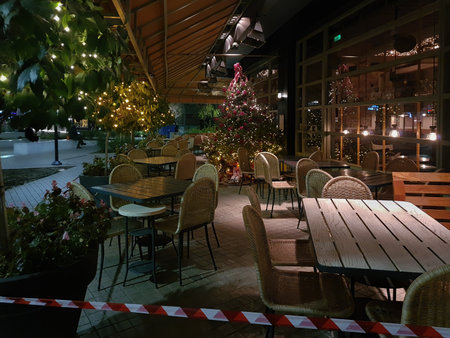Thessaloniki, Greece - December 18 2020: Hellenic empty restaurant with Christmas decoration.Bar at night without crowd and no access ribbon at outdoor seating area closed due to covid-19 measures.のeditorial素材