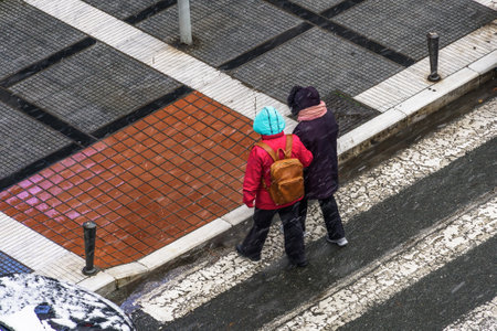 Thessaloniki, Greece - January 16 2019: Crowd on heavy snowfall at the city center. Unidentified people in warm clothes walk on zebra crossing under bad weather with snow falling.のeditorial素材