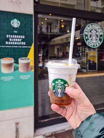 Thessaloniki, Greece â February 20 2021: Starbucks Cloud Macchiato takeaway coffee cup with a straw-less lid. Hand holding outside store a branded cold beverage with Medusa company logo.のeditorial素材