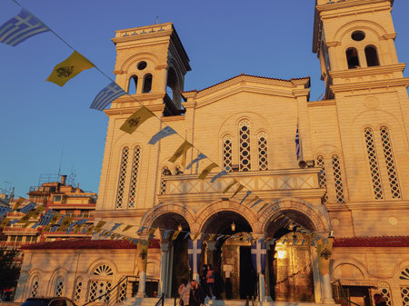 Thessaloniki, Greece - March 28 2021: People with covid-19 masks exit a church. Evening view of unidentified crowd with face protection outside an Orthodox church with Greek and Byzantine flags.のeditorial素材